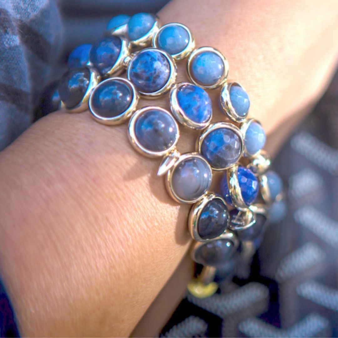 A close-up of a blue gemstone bracelet by Brett Lauren on a wrist, showing the beautiful blue tones of the stones in natural lighting.