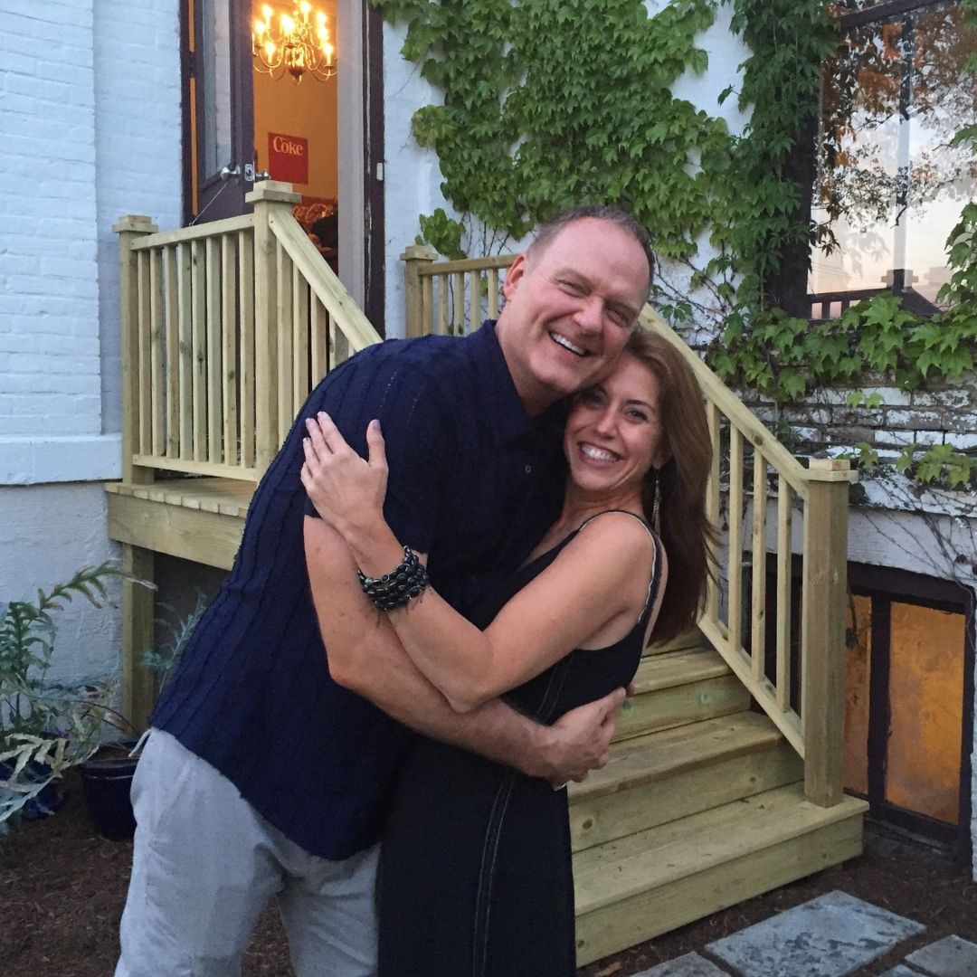 Brett Lauren, founder of Brett Lauren Jewelry, hugging a friend outside a home, smiling and showing a joyful moment.