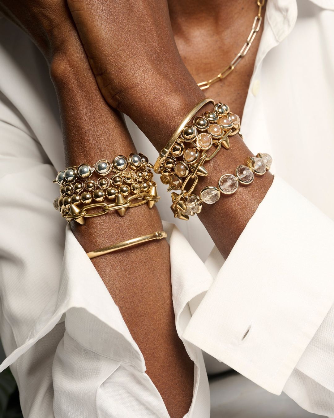 Close-up of elegant chain link bracelets in gold, stacked with gemstone accents, showcasing bold and versatile jewelry from Brett Lauren.