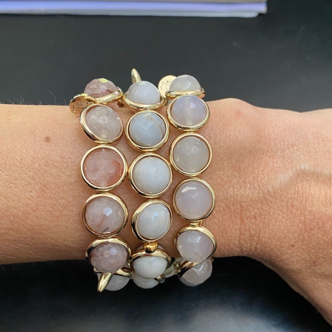 A close-up of a wrist wearing a Brett Lauren handcrafted gemstone bracelet featuring white and gold stones in an elegant design.