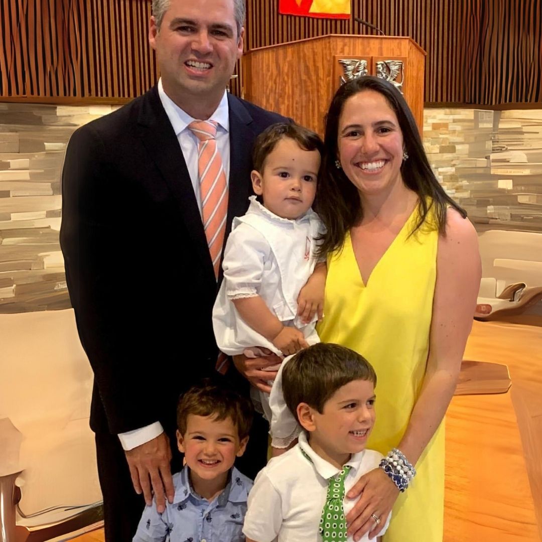 A family photo showing a woman wearing Brett Lauren gemstone bracelets, posing with her husband and two children, smiling in a formal setting.