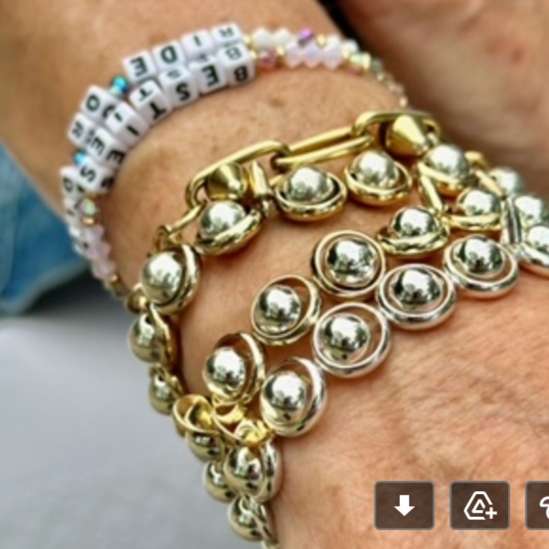 A wrist wearing stacked gold and silver gemstone bracelets by Brett Lauren, showcasing a blend of shiny, elegant designs.