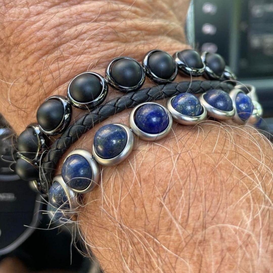 A man wearing Brett Lauren black and blue gemstone bracelets, styled in a casual setting while driving.