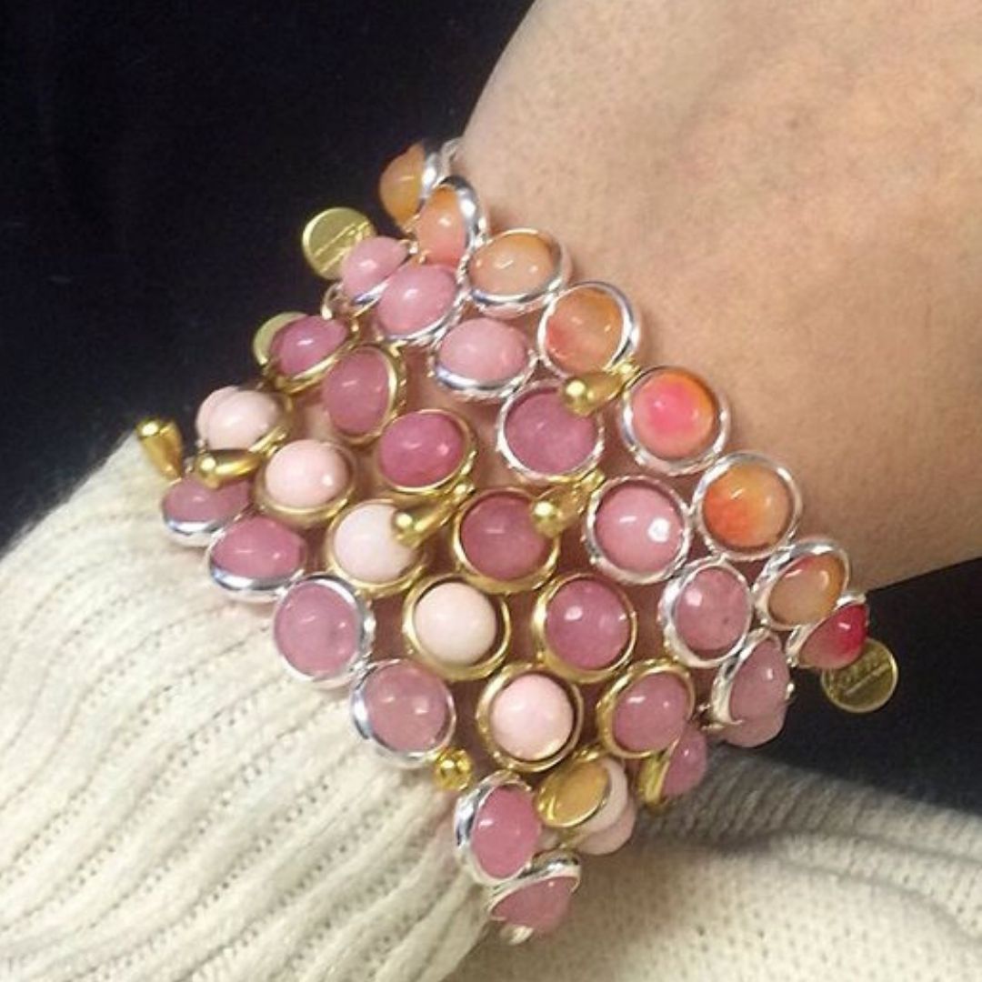 A close-up of a wrist adorned with a pink and white gemstone bracelet by Brett Lauren, styled with a cozy sweater.