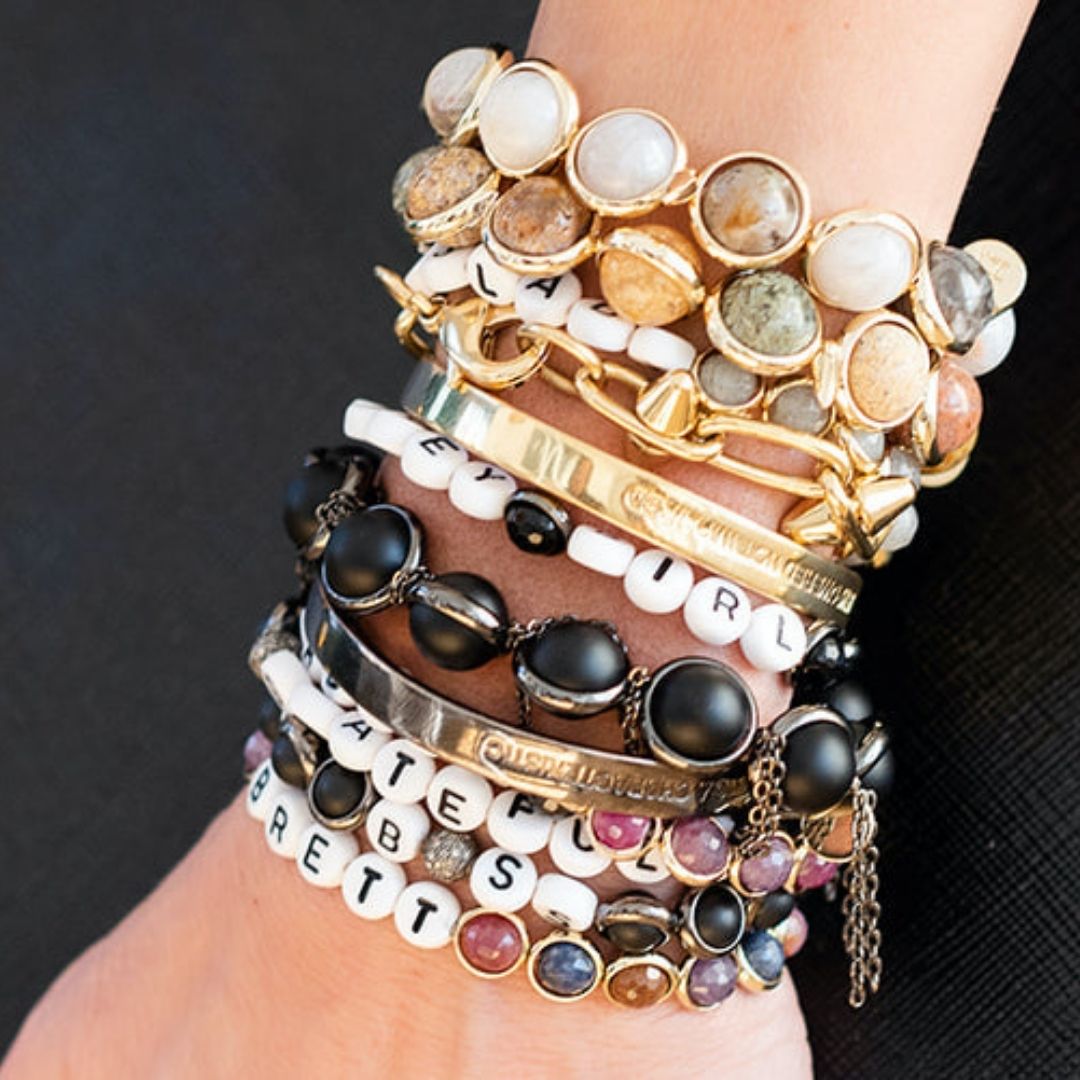 A close-up of a wrist adorned with stacked black, white, and gold gemstone bracelets by Brett Lauren, showcasing a bold and elegant combination of designs.