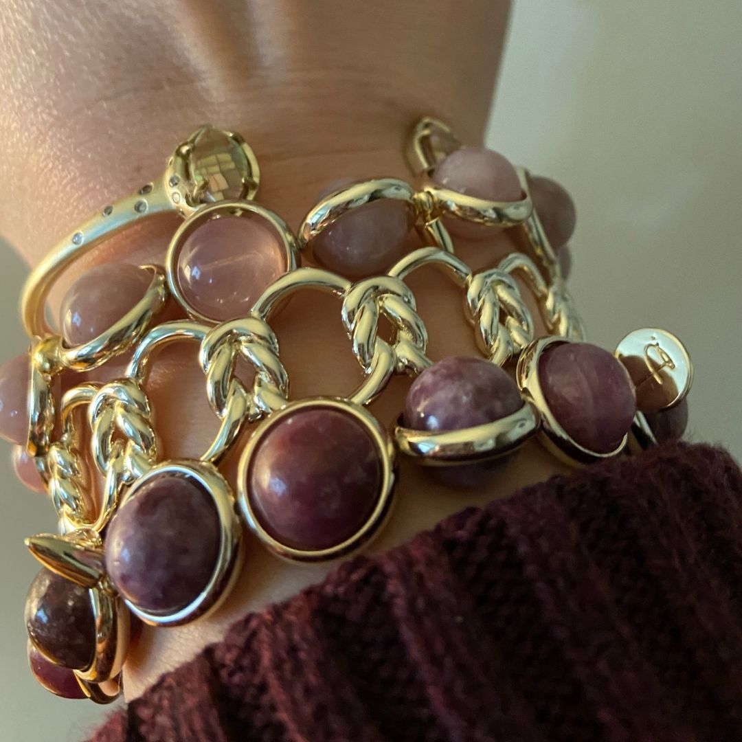 A wrist adorned with stacked brown and gold gemstone bracelets by Brett Lauren, styled with a cozy sweater for a fall look.