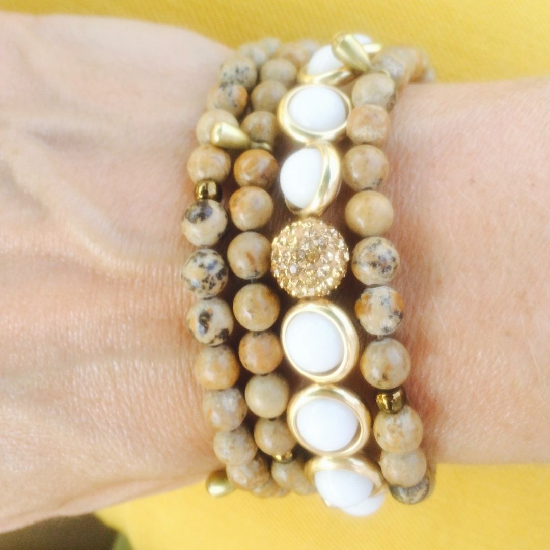 A close-up of a wrist adorned with stacked black, white, and gold gemstone bracelets by Brett Lauren, showcasing a bold and elegant combination of designs.